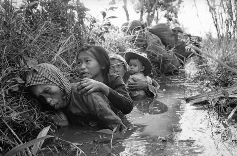 Wanita dan anak-anaknya berusaha untuk melarikan diri daripada pertempuran antara Viet Cong dan tentera Amerika Syarikat. Dirakam 20km daripada Saigon pada Januari 1966.